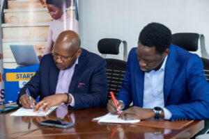 Rt. Hon. Calvin Armstrong Rwomiire Akiiki and r. Okello Robert Bob append signatures to the MOU.
